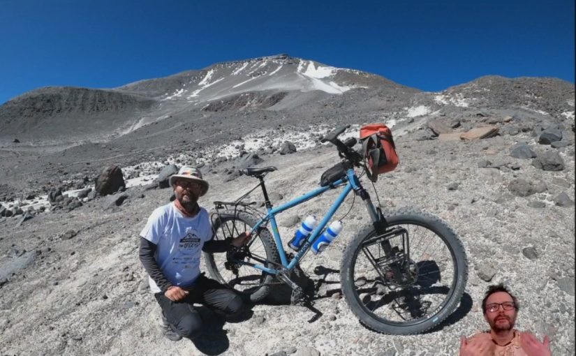 Mężczyzna z rowerem na tle wulkanu, który był celem wyprawy