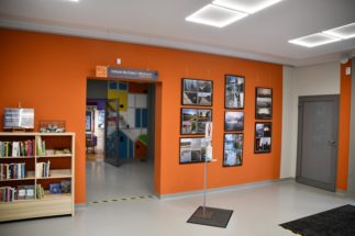 hol biblioteki, po lewej półka z ksiazkami, po prawej ramy ze zdjęciami konkursowymi